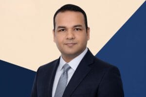 Portrait of Dr. Vikram Singh, Head of Artificial Intelligence, Mahindra Group on a geometric blue and beige background.