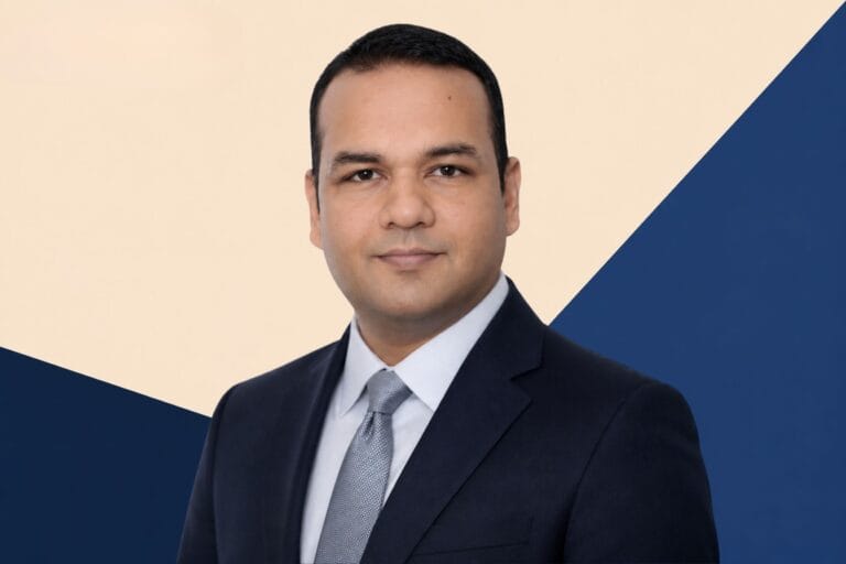 Portrait of Dr. Vikram Singh, Head of Artificial Intelligence, Mahindra Group on a geometric blue and beige background.